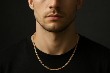 Professional product photograph of a delicate gold curb chain necklace on a young man positioned directly face-on